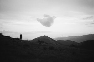 image en noir et blanc : une montage, une silhouette et un nuage